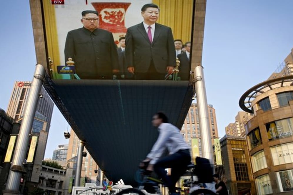 Auf einem riesigen Bildschirm in Peking wird die Begrüßung von Kim Jong Un und Xi Jinping übertragen.