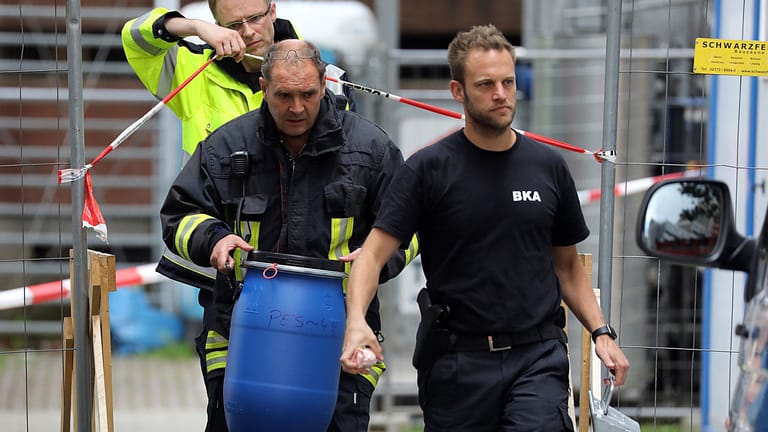 Ein Feuerwehrmann trägt eine blaue Tonne aus dem Wohnkomplex Osloerstraße 3 in Köln-Chorweiler: Die Ermittler fanden dort 2000 giftige Rizinussamen.