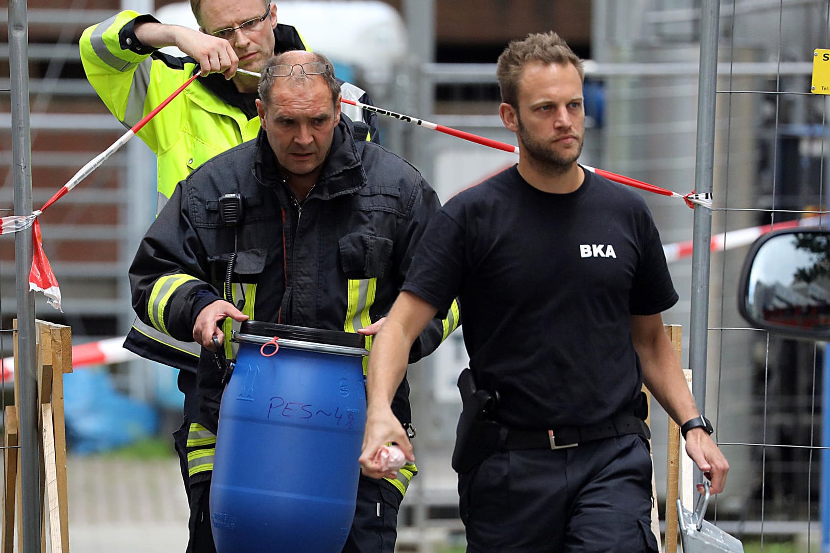 Ein Feuerwehrmann trägt eine blaue Tonne aus dem Wohnkomplex Osloerstraße 3 in Köln-Chorweiler: Die Ermittler fanden dort 2000 giftige Rizinussamen.