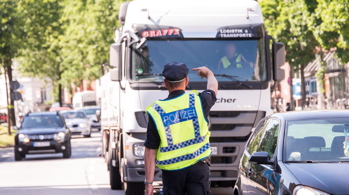 Ein Polizist hält einen Lastwagenfahrer für eine Kontrolle an: Wegen zu schmutziger Luft gilt in Hamburg auf einigen Straßen im Stadtteil Altona ein Fahrverbot für Fahrzeuge mit Diesel-Motoren bis zur Abgasnorm Euro5.