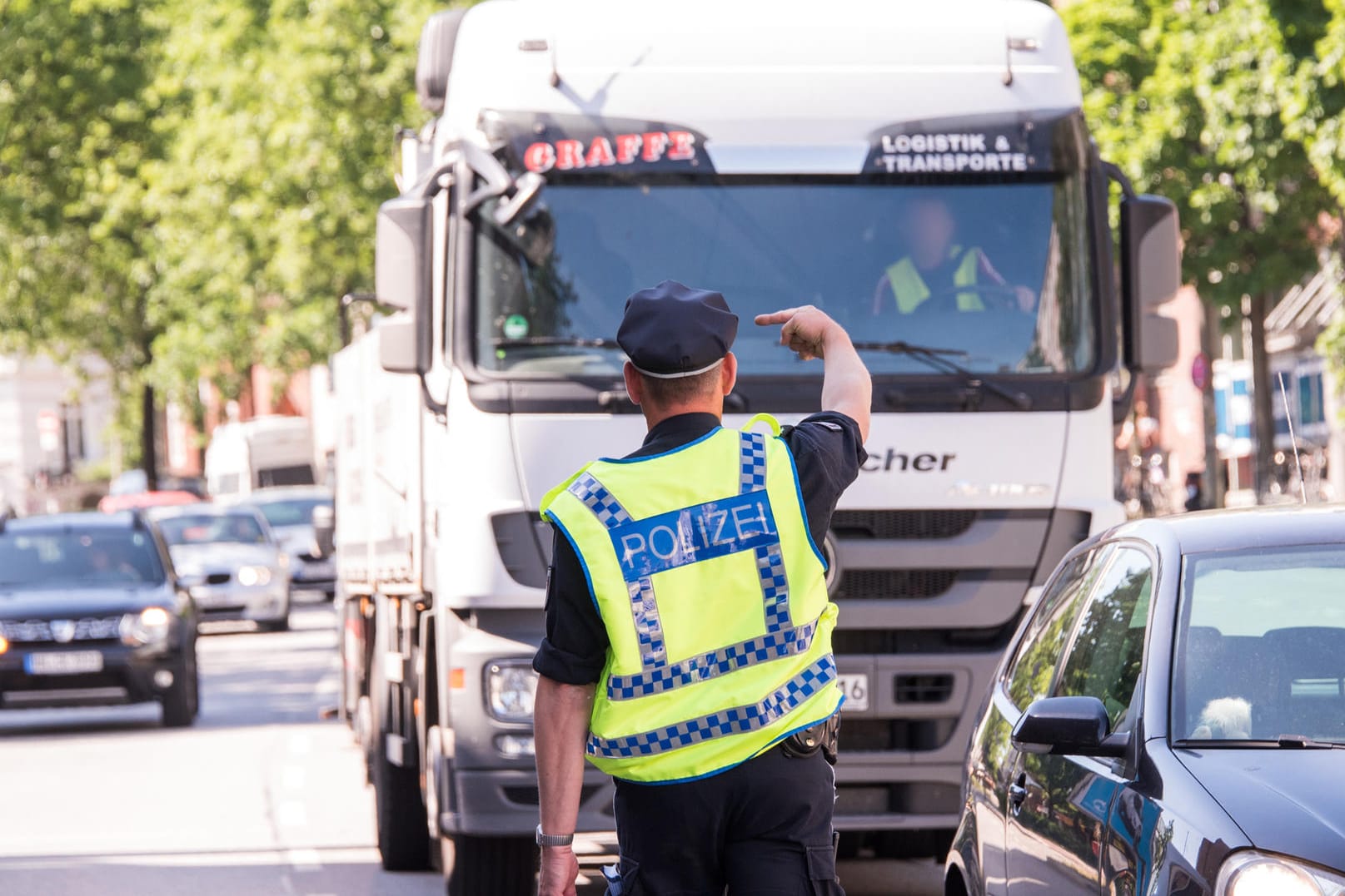Ein Polizist hält einen Lastwagenfahrer für eine Kontrolle an: Wegen zu schmutziger Luft gilt in Hamburg auf einigen Straßen im Stadtteil Altona ein Fahrverbot für Fahrzeuge mit Diesel-Motoren bis zur Abgasnorm Euro5.