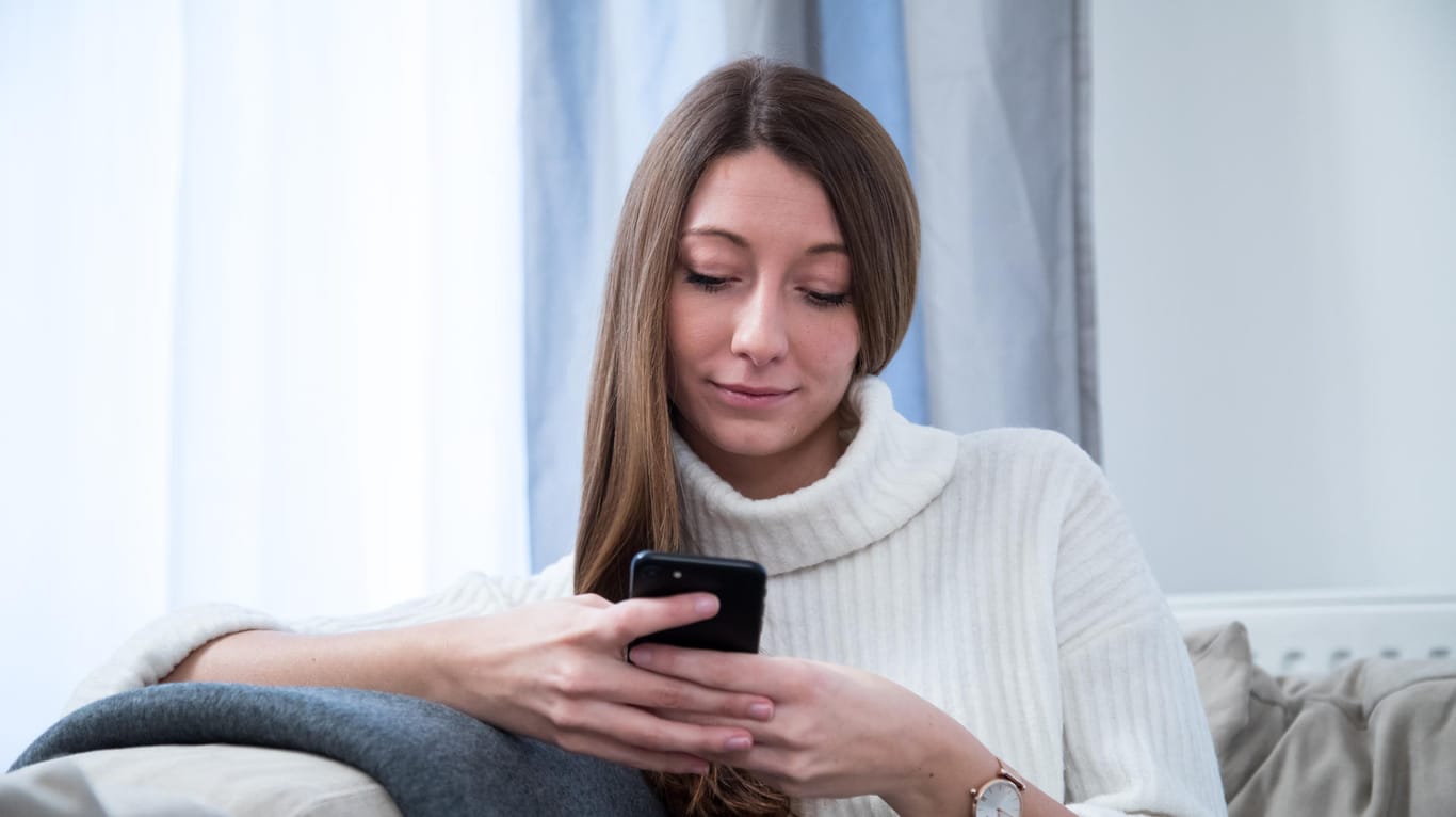 Eine Frau benutzt ein Smartphone: Dank einer App lassen sich Fotos auch per WLAN an den Rechner schicken.