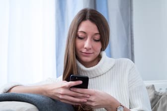 Eine Frau benutzt ein Smartphone: Dank einer App lassen sich Fotos auch per WLAN an den Rechner schicken.