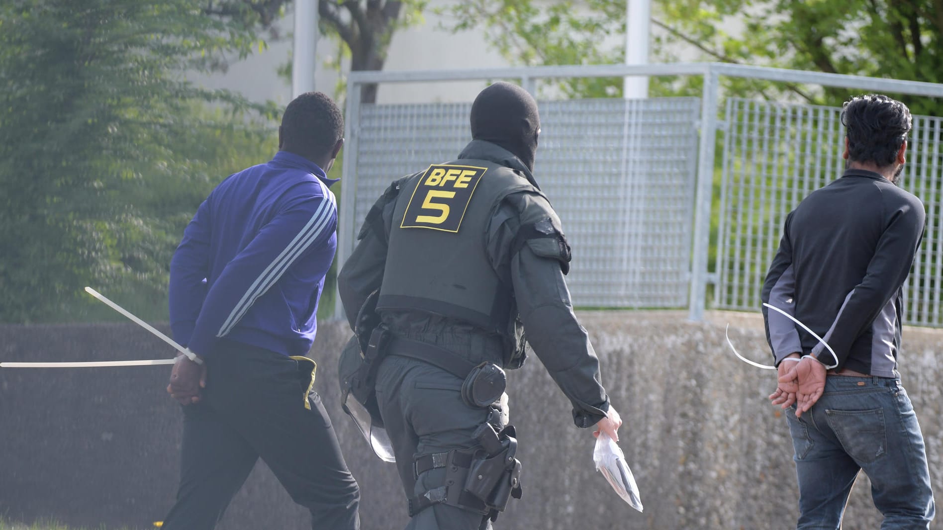 Ein Polizist und zwei Festgenommene bei der Razzia in Ellwangen Anfang Mai: Im Zuge des Einsatzes wurden 37 Strafverfahren eingeleitet.