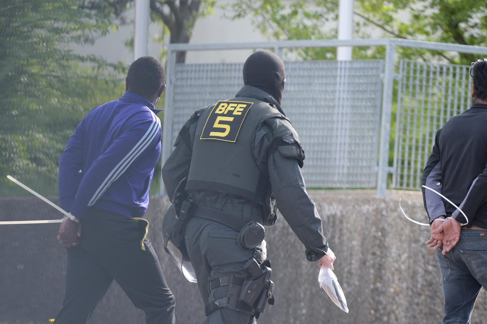 Ein Polizist und zwei Festgenommene bei der Razzia in Ellwangen Anfang Mai: Im Zuge des Einsatzes wurden 37 Strafverfahren eingeleitet.