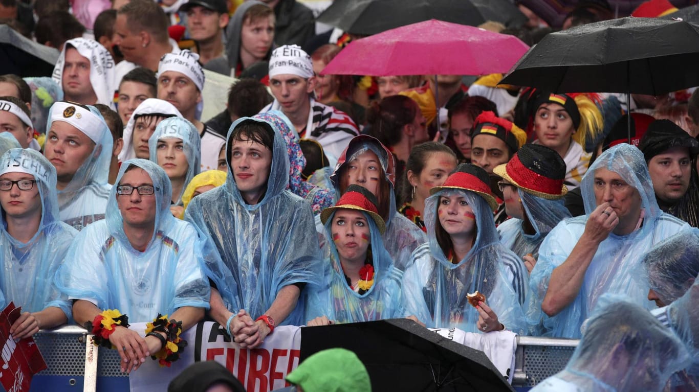 Fans auf der verregneten Berliner Fanmeile bei der WM 2014: Während des Spiels gegen Schweden kann es in Deutschland ähnlich schlechtes Wetter geben.