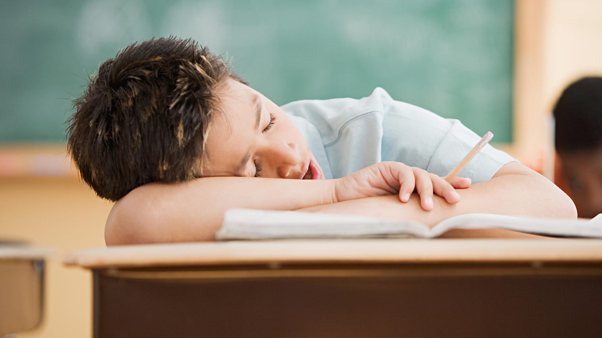 Junge schläft in der Schule auf dem Tisch.