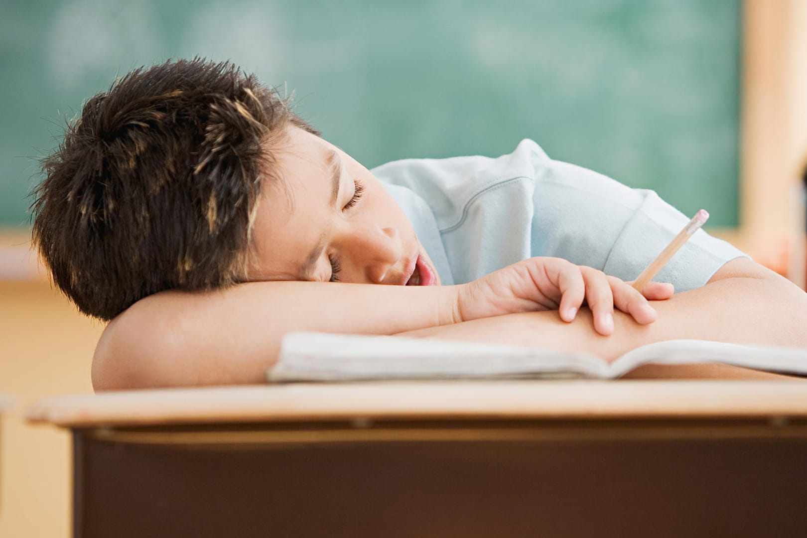 Junge schläft in der Schule auf dem Tisch.