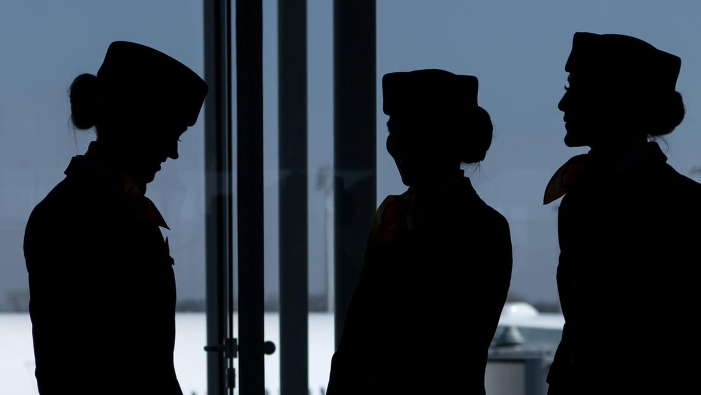 Flugbegleiterinnen stehen am Flughafen vor einem Fenster am Terminal.