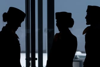 Flugbegleiterinnen stehen am Flughafen vor einem Fenster am Terminal.