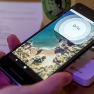 Google Pay: Ein Gast demonstriert mit einem Smartphone und der App des neuen Bezahldienstes in einem Café das Bezahlen mit dem Handy.