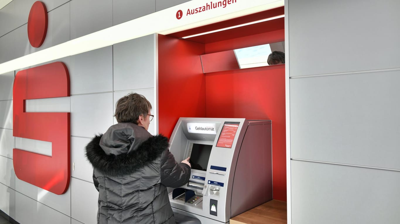 Eine Frau hebt Geld am Automaten ab: Sparkassen-Kunden sollen bald mit dem Smartphone bezahlen können.