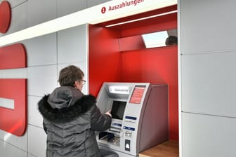 Eine Frau hebt Geld am Automaten ab: Sparkassen-Kunden sollen bald mit dem Smartphone bezahlen können.