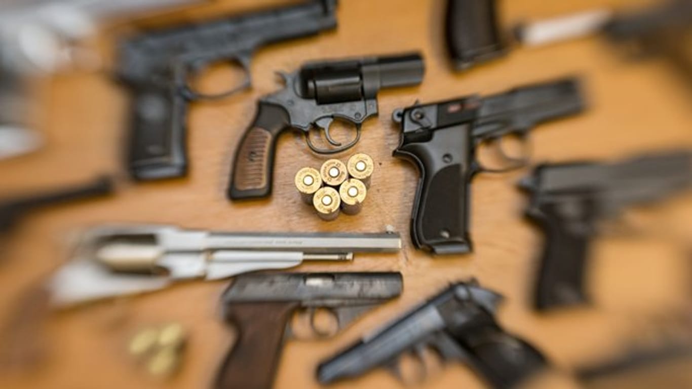 Pistolen, Revolver und Munition auf einem Tisch in der gesicherten Asservatenkammer der Waffenbehörde eines Landkreises.