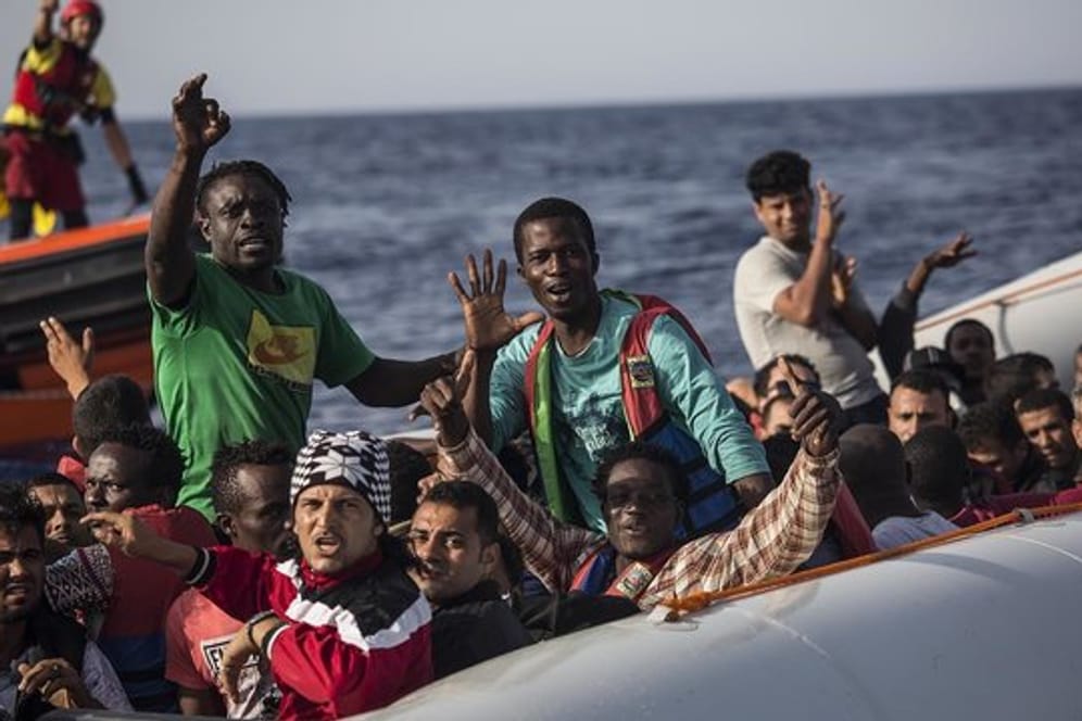 Migranten in einem Schlauchboot winken vor der Küste Libyens zu einem Mitglied der Hilfsorganisation Proactiva Open Arms.