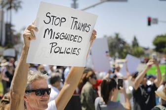 Menschen protestieren in Carlsbad, Kalifornien, mit Schildern gegen die US-Einwanderungspolitik.