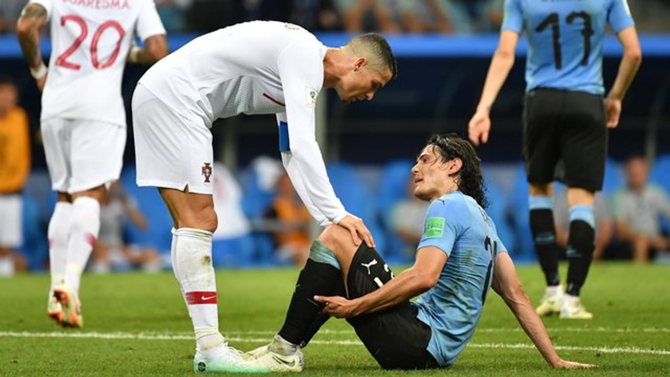 Cristiano Ronaldo (l) hilft dem verletzten Edinson Cavani aus Uruguay vom Platz.