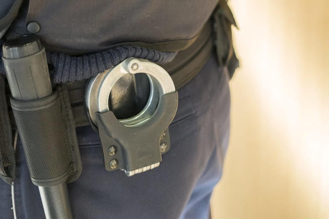 Polizist mit Handschellen: Die Wohnung der ehemaligen IS-Anhängerin wurde von Ermittlern durchsucht. (Symbolbild)