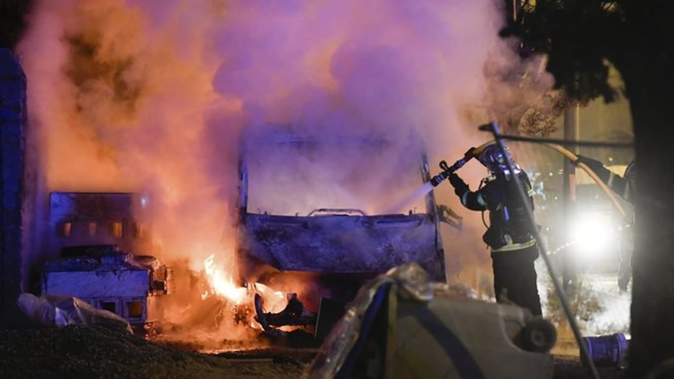 Ein Feuerwehrmann löscht einen angezündeten Lastwagen.