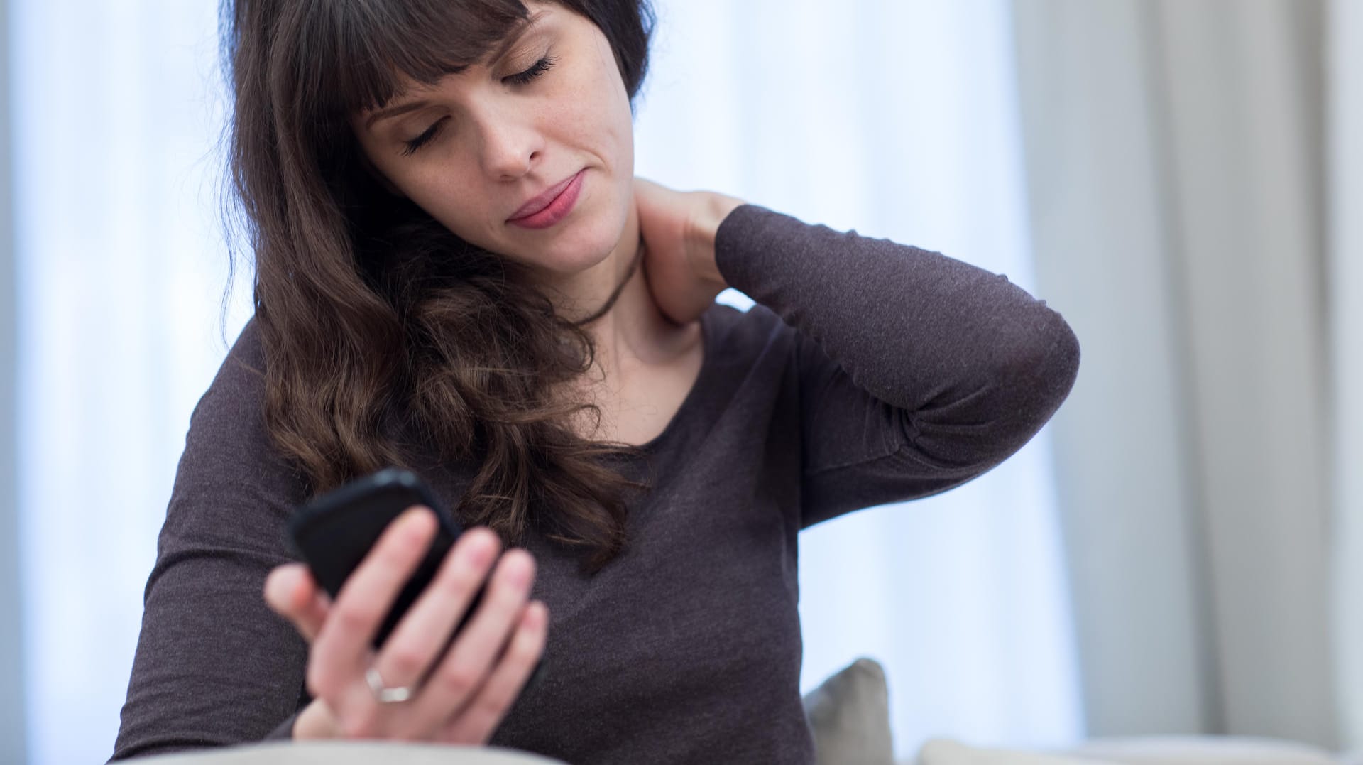 Schmerzen im Nackenbereich: Wer ständig in unnatürlicher Haltung aufs Smartphone schaut, leidet am sogenannten Handynacken.