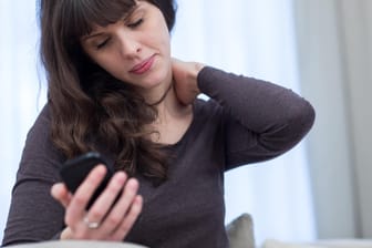 Schmerzen im Nackenbereich: Wer ständig in unnatürlicher Haltung aufs Smartphone schaut, leidet am sogenannten Handynacken.