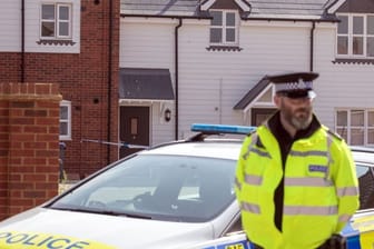 Britischer Polizist neben seinem Polizeiauto nahe der dem Ermittlungsort.