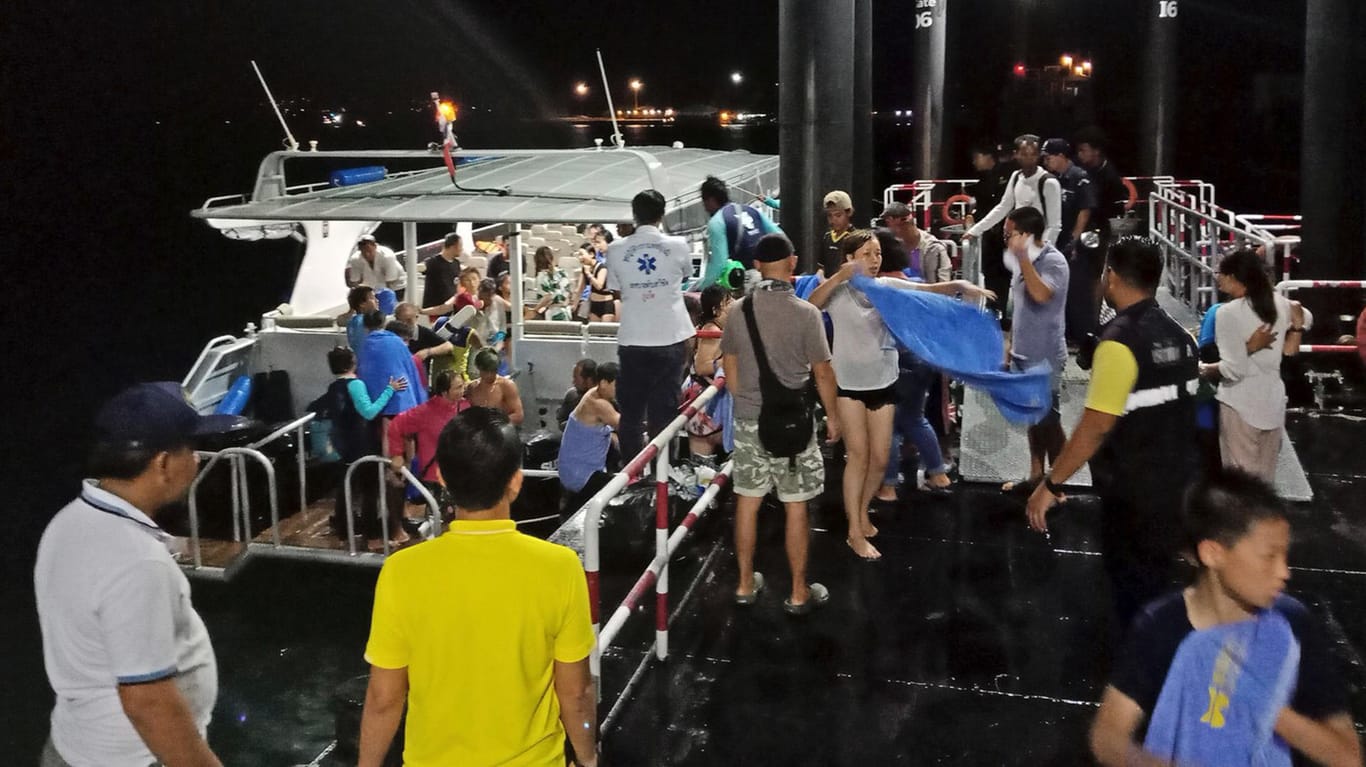 Ein Boot bringt gerettete Touristen an Land: Vor der Küste Thailands sind zwei Schiffe untergegangen.
