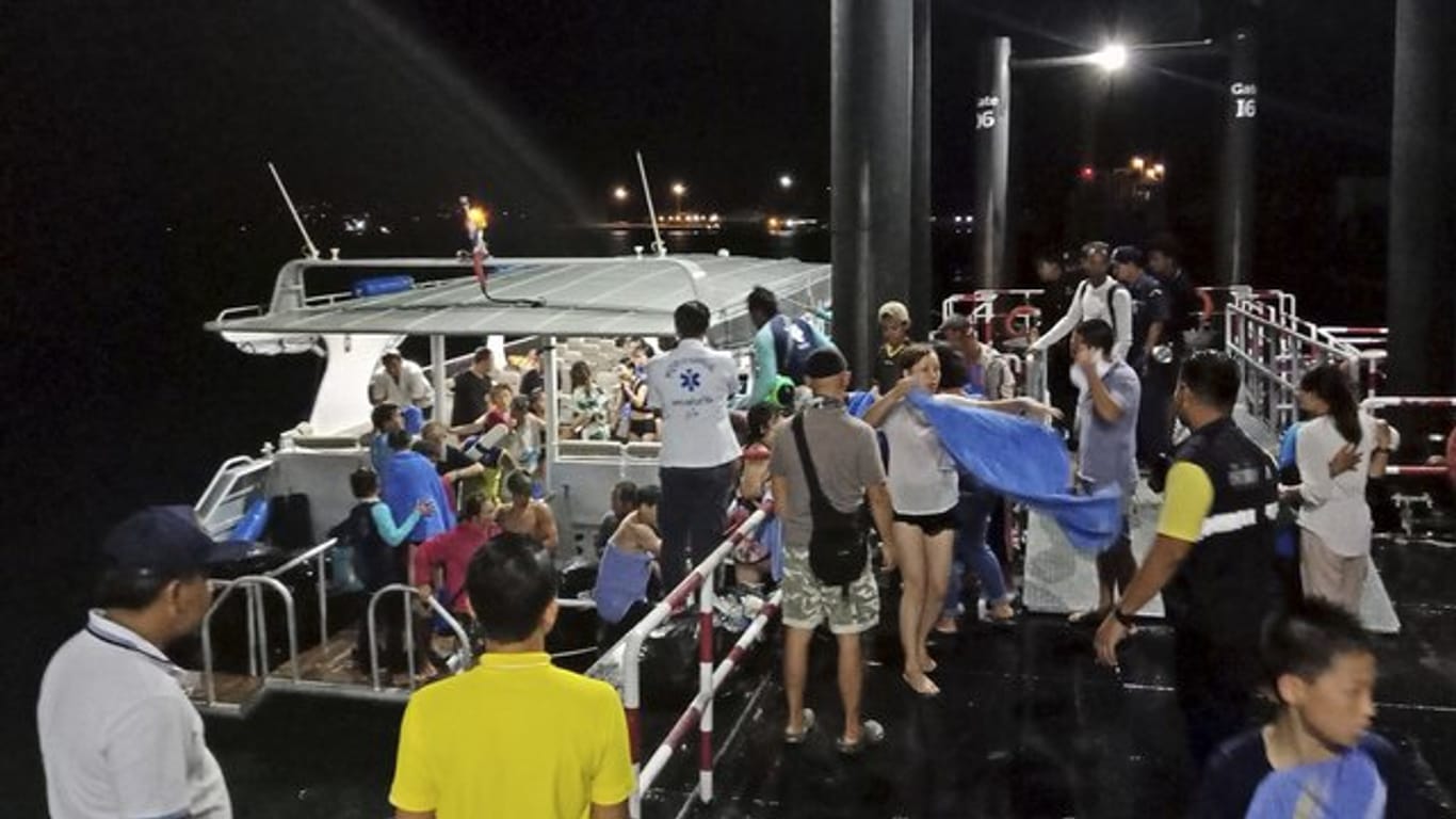 Touristen, die von einem sinkenden Boot gerettet worden sind, werden ans Festland begleitet.