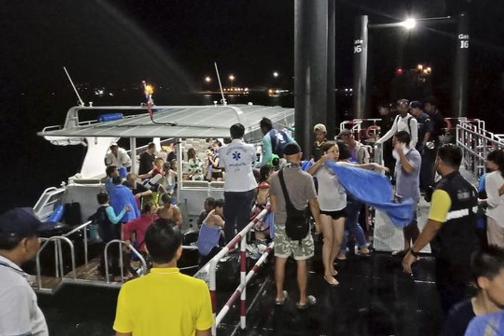 Touristen, die von einem sinkenden Boot gerettet worden sind, werden ans Festland begleitet.