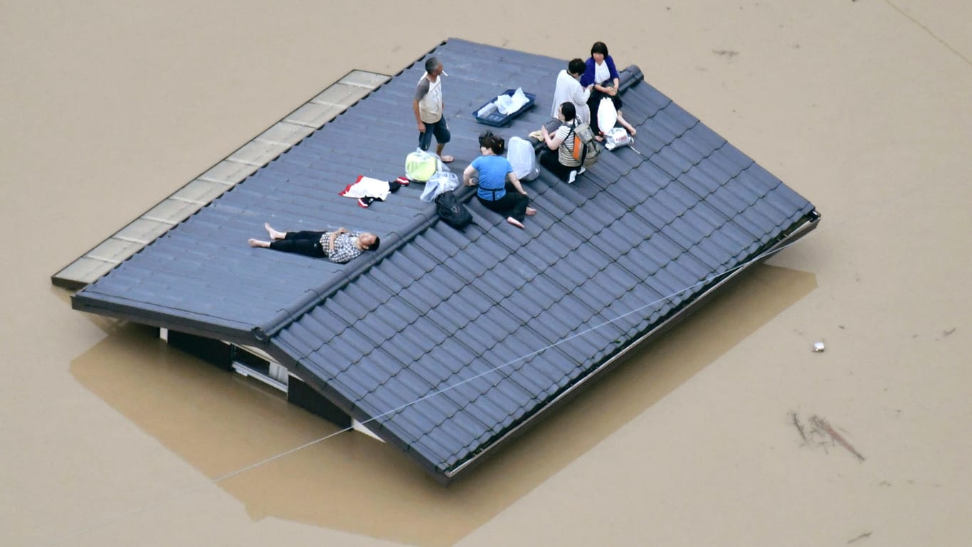 Menschen warten auf dem Dach eines Hauses im japanischen Kurashiki auf Rettung: Im Westen des Landes mussten mindestens 440.000 Menschen ihre Häuser und Wohnungen verlassen.