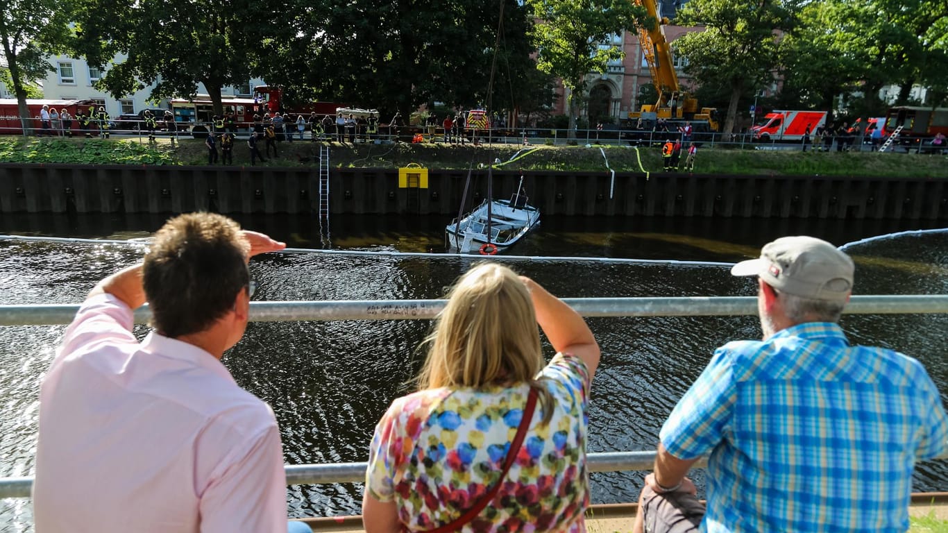 Passanten beobachten das sinkende Ausflugsboot. Die Passagiere konnten sich über das Ufer in Sicherheit bringen.