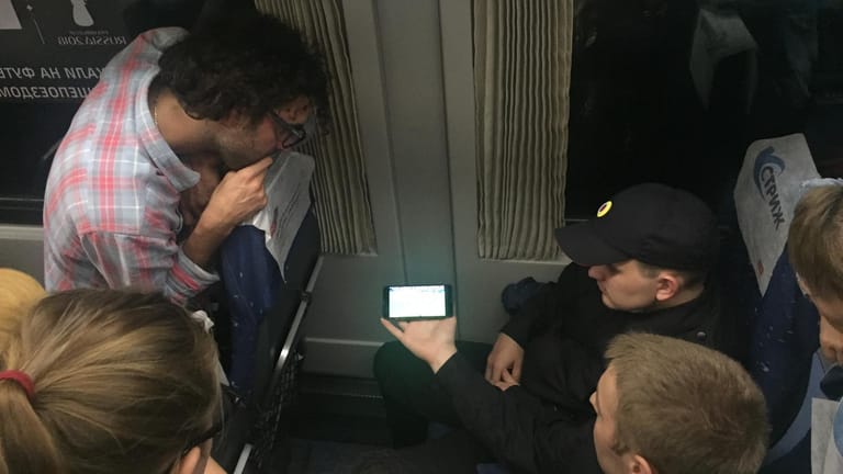 Im Zug nach Moskau: Russische Polizisten (r.) gucken das Spiel per Livestream auf dem Handy. Andere Fahrgäste schauen ebenfalls zu.