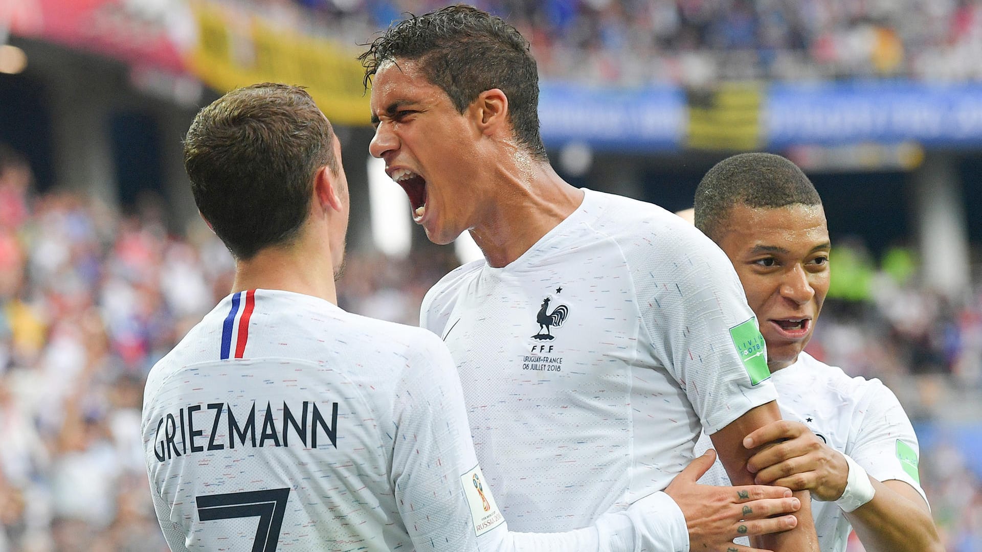 Antoine Griezmann (l.) und Kylian Mbappé (r.) feiern mit Raphael Varane dessen Treffer gegen Uruguay.