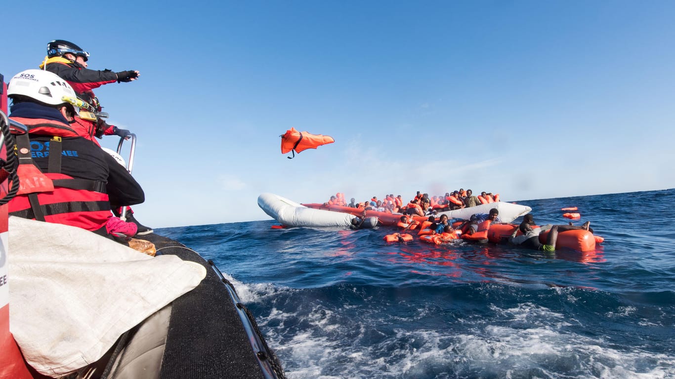 Mitarbeiter der Hilfsinitiative SOS Mediterranee werfen Flüchtlingen vor der libyschen Küste Rettungswesten zu.