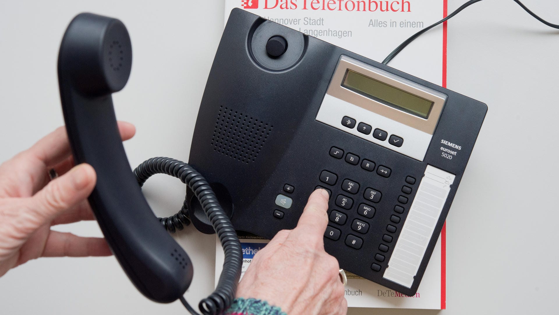 Ein Telefon und ein Telefonbuch liegen auf einem Tisch: Lange Zeit war das Telefon die einzige Möglichkeit, um an Informationen zu erfragen. (Archivbild)