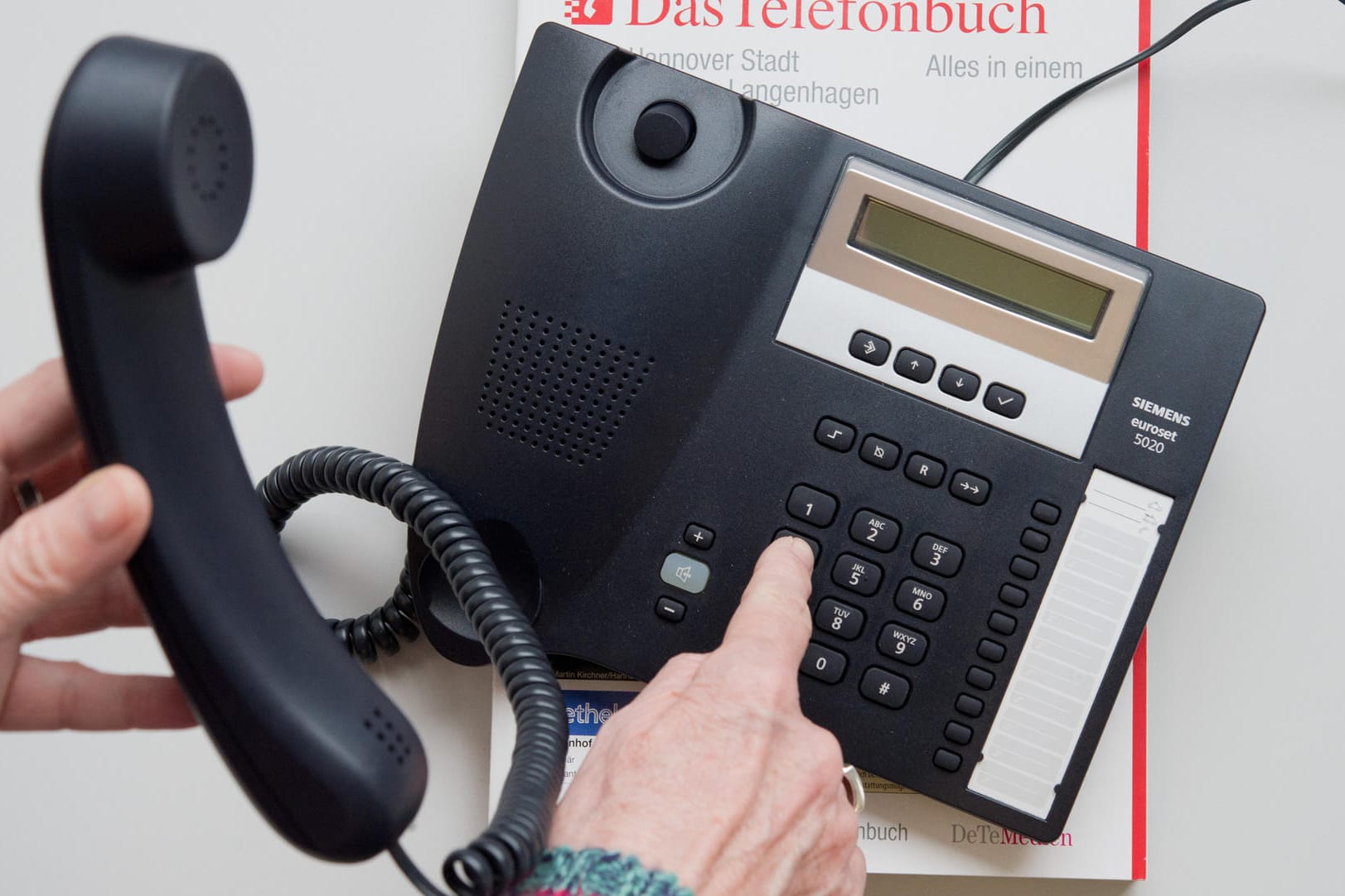 Ein Telefon und ein Telefonbuch liegen auf einem Tisch: Lange Zeit war das Telefon die einzige Möglichkeit, um an Informationen zu erfragen. (Archivbild)