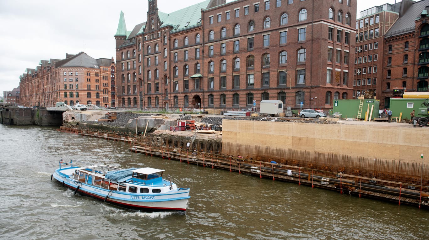 Hamburg: Eine Barkasse passiert eine Baustelle an einer Kaimauer in der Speicherstadt.