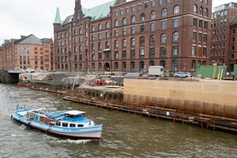 Hamburg: Eine Barkasse passiert eine Baustelle an einer Kaimauer in der Speicherstadt.