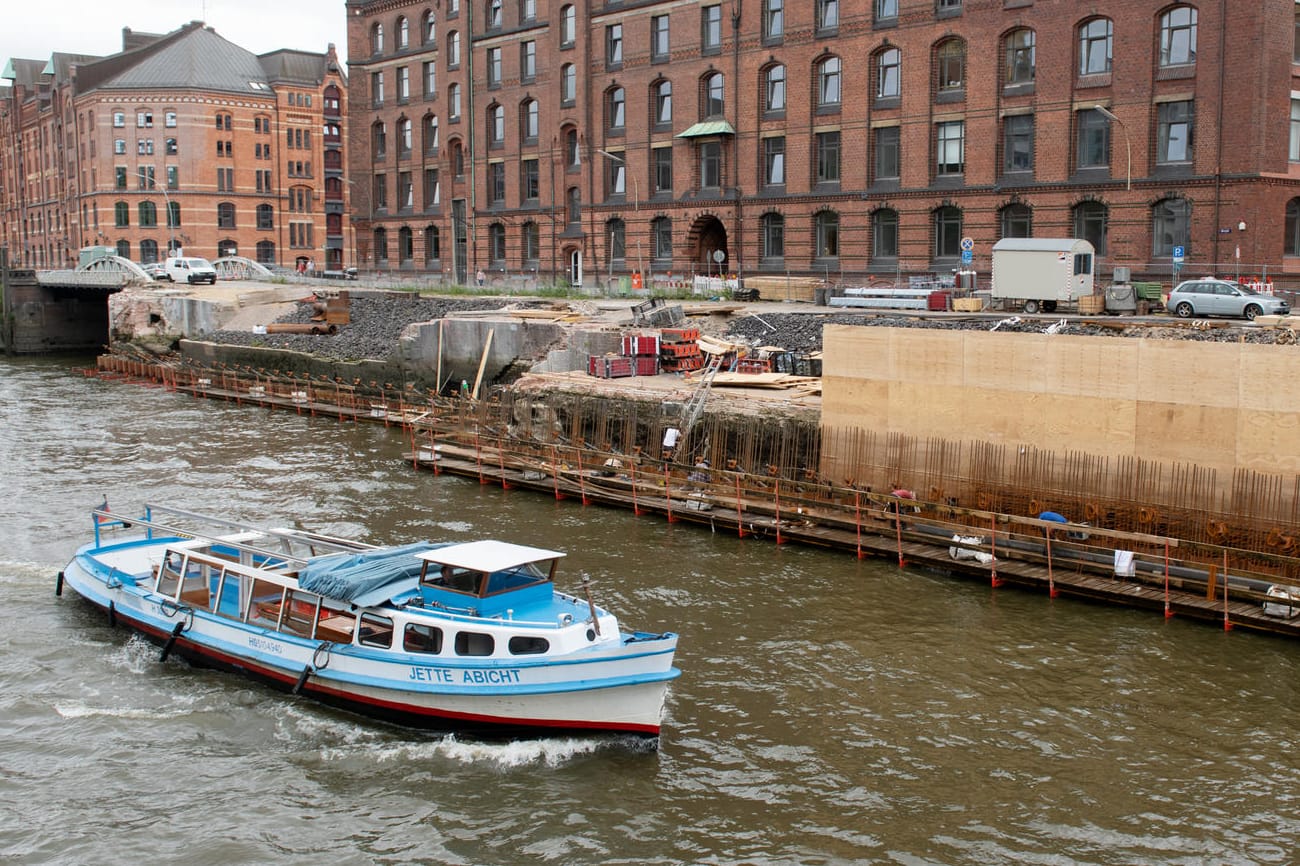 Hamburg: Eine Barkasse passiert eine Baustelle an einer Kaimauer in der Speicherstadt.