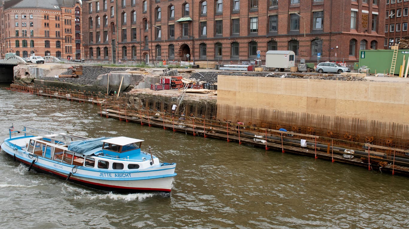 Hamburg: Eine Barkasse passiert eine Baustelle an einer Kaimauer in der Speicherstadt.