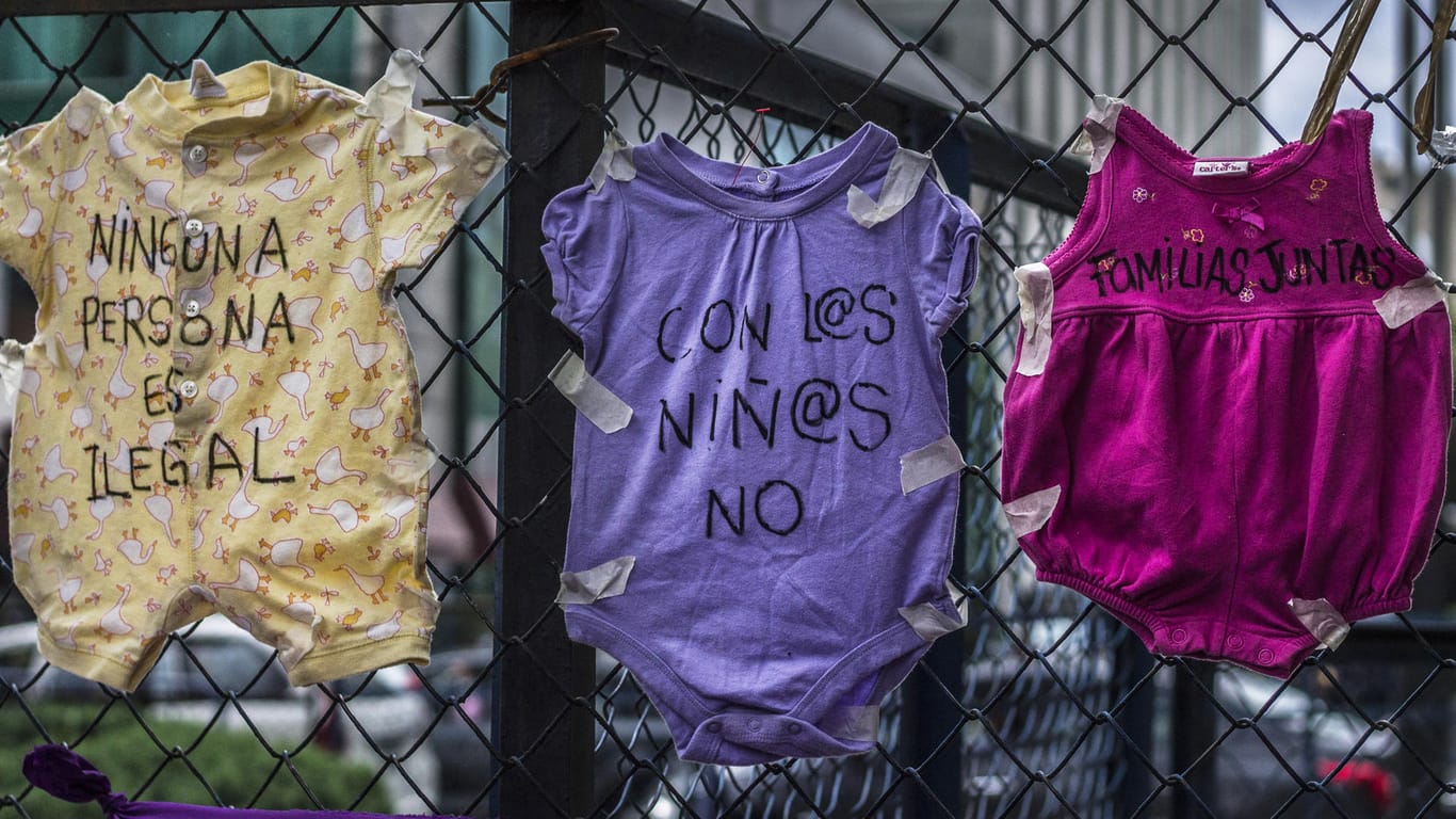 Kinderkleidung an einem Zaun in Mexiko: "Kein Mensch ist illegal" (l), "Familien (gehören) zusammen" (r), steht auf Strampelanzügen bei einem Protest gegen die US-Migrationspolitik vor der US-Botschaft in der mexikanischen Hauptstadt.