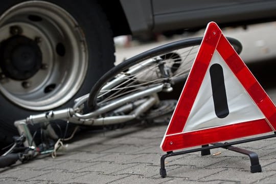 Ein Fahrrad liegt zu Anschauungszwecken bei einer Verkehrserziehungswoche für Schulen unter den Hinterrädern eines Lkw.
