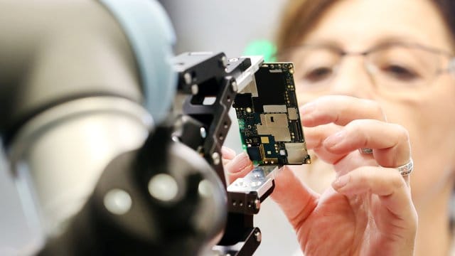 Eine Gigaset Mitarbeiterin und ein Roboter montieren das Smartphone GS 185 von Gigaset in Bocholt. Eine Gigaset Mitarbeiterin und ein Roboter montieren das Smartphone GS 185 von Gigaset in Bocholt.