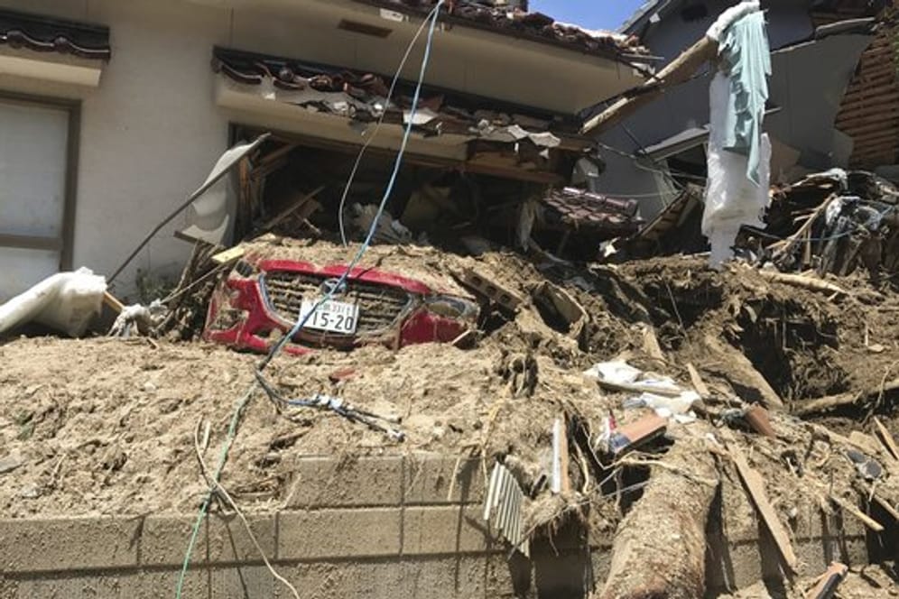 Ein Auto ist unter Schlamm und Schutt eines zerstörten Hauses begraben, nachdem es nach schweren Regenfällen zu Erdrutschen kam.