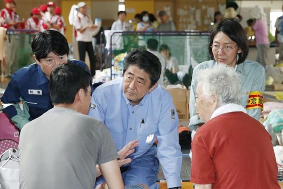 Japans Ministerpräsident Shinzo Abe (M) besucht eine Notunterkunft für Flutopfer im westjapanischen Kurashiki.