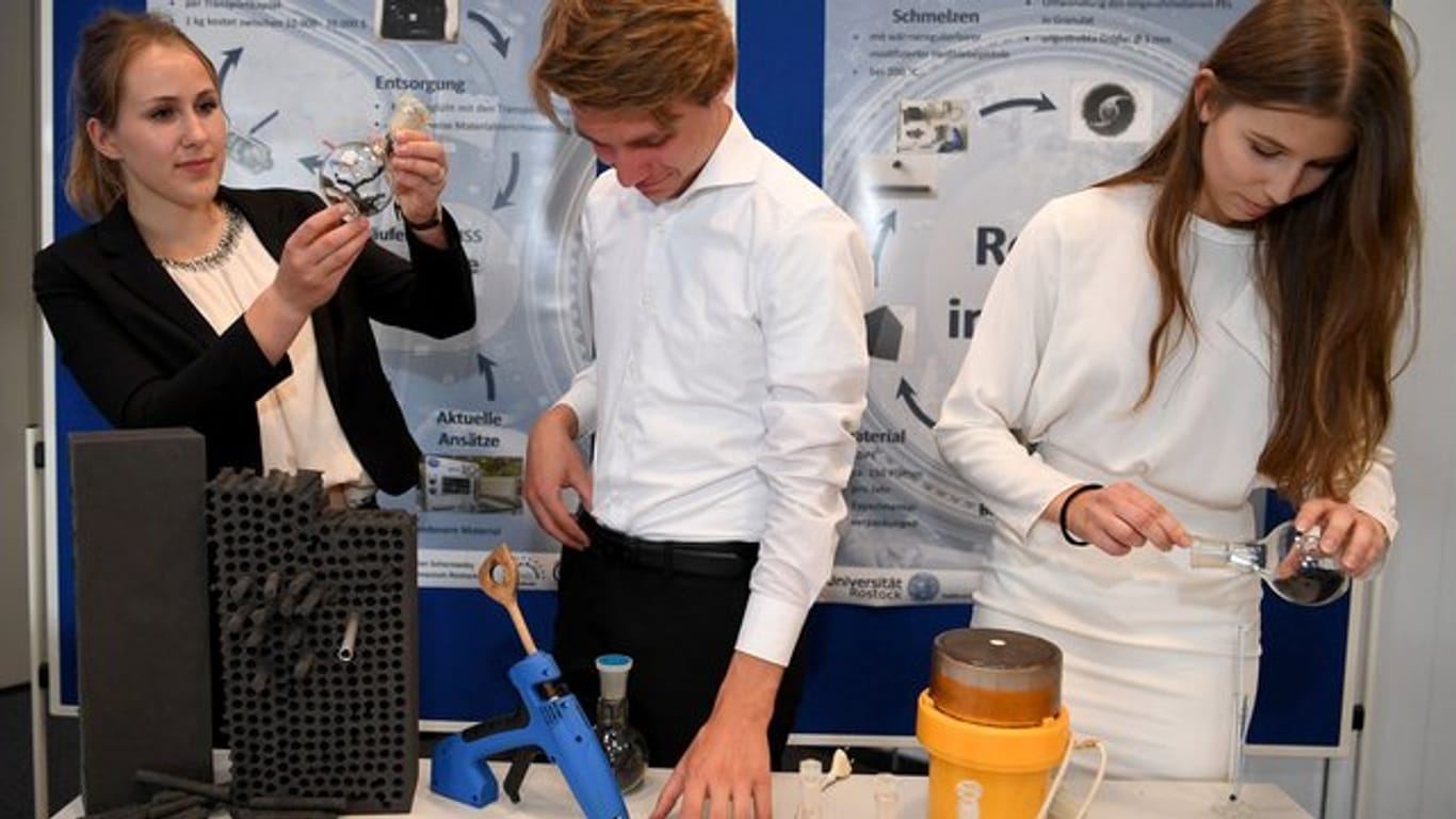 Die Rostocker Schülerinnen Leni Termann (l), Lara Maria Neubert und Schüler Adrian Schorowsky präsentieren ihre Forschungsarbeit in einen Raum bei Airbus.