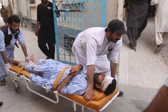 Eine verletzte Person wird in ein Krankenhaus gebracht: Bei zwei Anschlägen auf Wahlkampfveranstaltungen in Pakistan sind am Freitag über hundert Menschen gestorben.