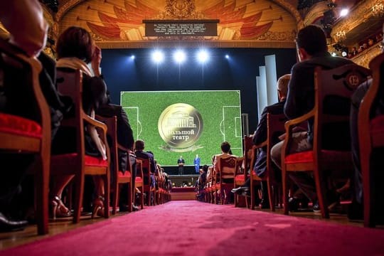 Russlands Präsident Wladimir Putin (l) steht auf der Bühne des Bolschoi-Theaters neben FIFA-Chef Gianni Infantino und hält eine Rede.