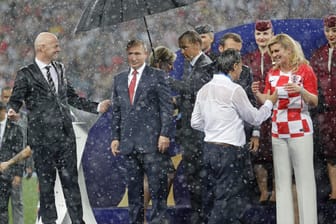 Starker Regen im Luschniki-Stadion: Während Wladimir Putin (2. v.l.) ein Schirm gereicht wird, werden die kroatische Präsidentin Kolinda Grabar-Kitarovic (vo. re. mit Trainer Zlatko Dalic) und Emmanuel Macron (l. daneben) pitschnass.