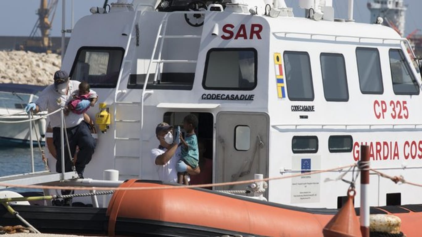 Sanitäter tragen in Pozzallo (Sizilien) Kinder von Bord eines Schiffes der italienischen Küstenwache.